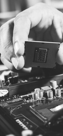 Black and white photo showing a hand holding a chip over motherboard