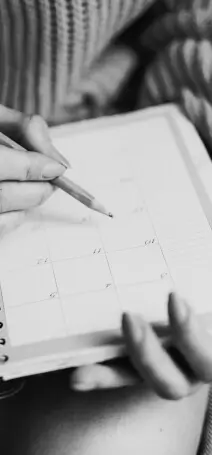 Black and white photo showing someone writing in a calendar book