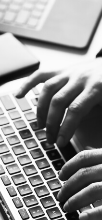 Black and white photo showing hands typing on a keyboard