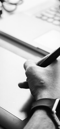 Black and white photo showing a hand drawing on a graphic tablet