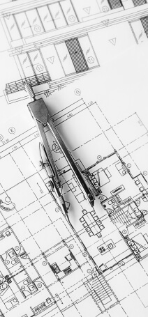 Black and white photo showing house plans with a caliper