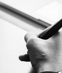 Black and white photo showing a hand drawing on a graphic tablet