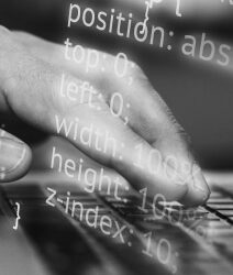 Black and white photo showing a part of CSS code and a hand typing on a keyboard